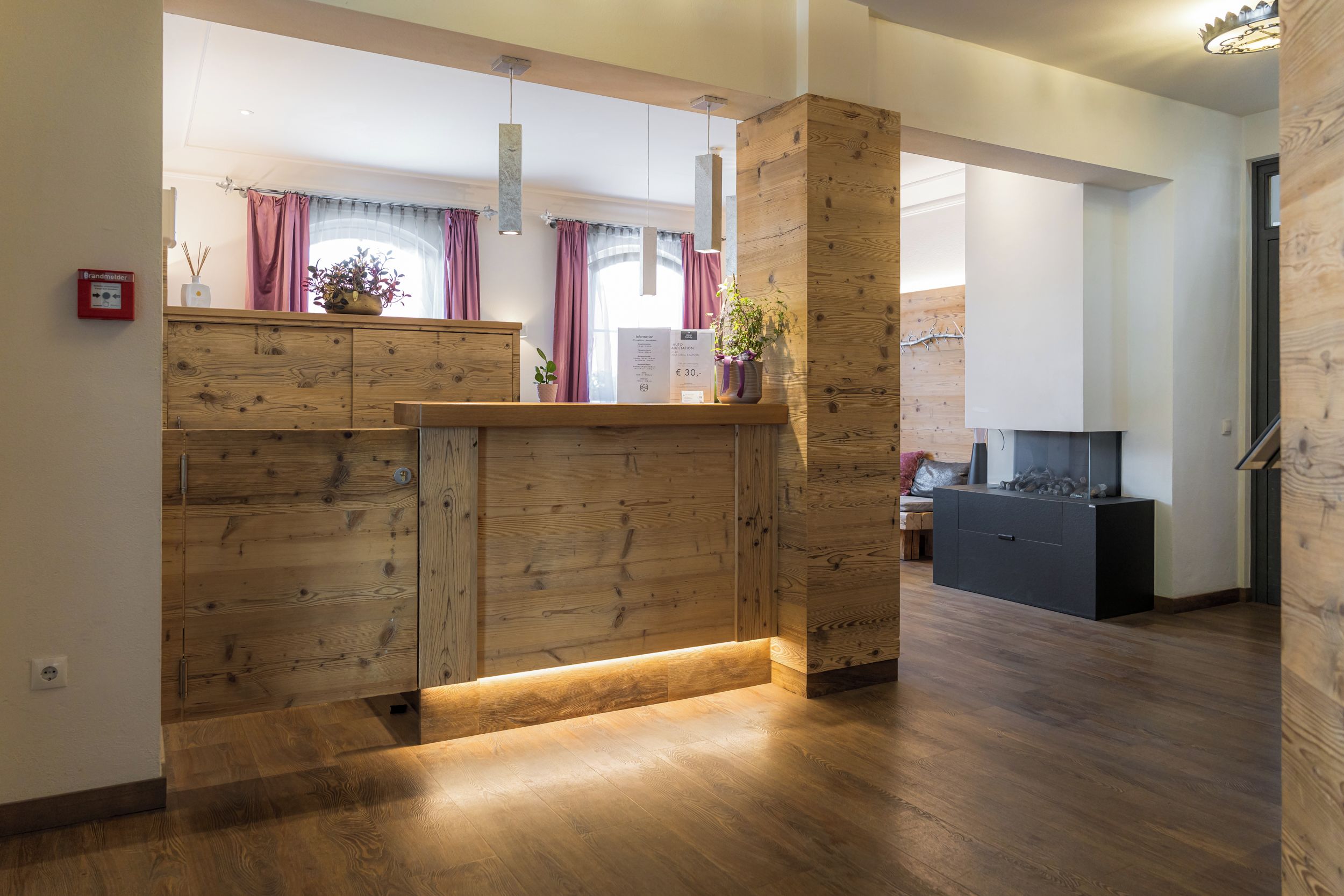 A modern interior with wooden paneling, a reception desk, and a television in the background.