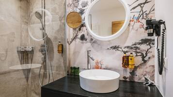 Een badkamer met een ronde spiegel, een wastafel en een douche.