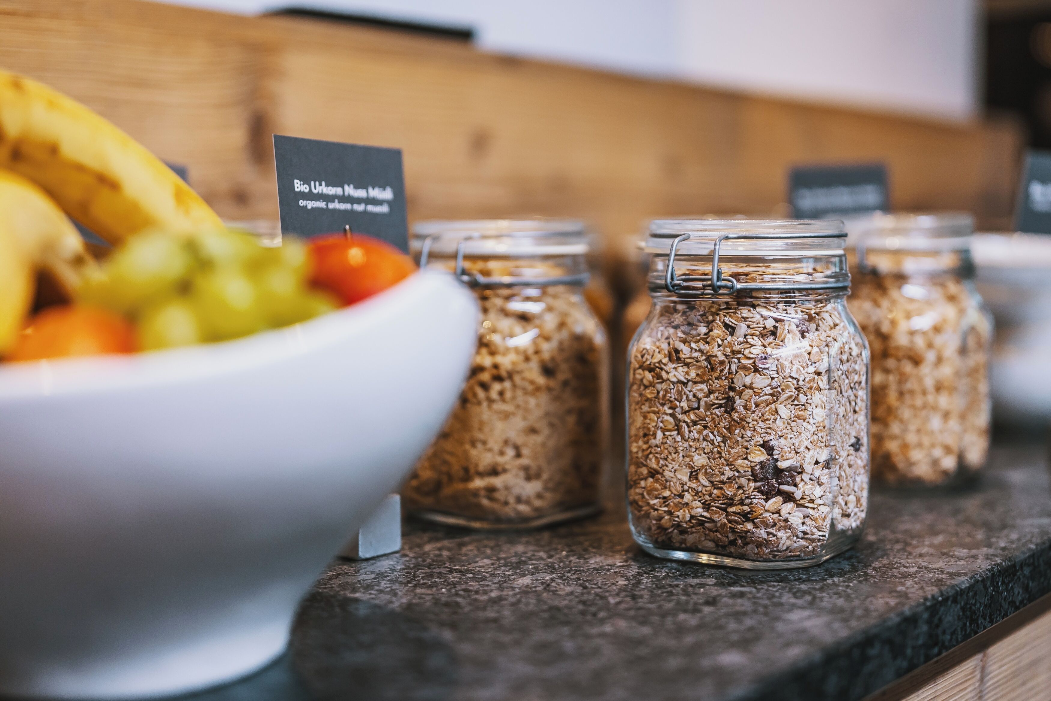 A breakfast buffet with a bowl of fruit and granola jars.