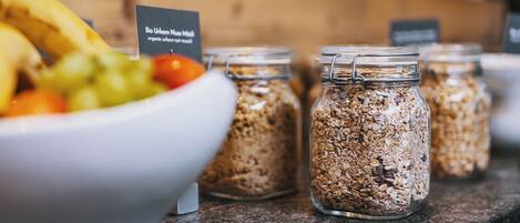 A breakfast buffet with a bowl of fruit and granola jars.
