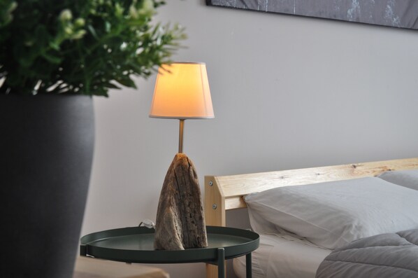 A bed with a wooden headboard, a bedside table with a lamp, and a potted plant.