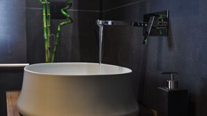 Moderni kylpyhuone, jossa on suuri, pyöreä pesuallas, hana ja saippua-annostelija.