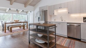 A modern kitchen with wooden cabinets, stainless steel appliances, and a dining area with a wooden table and chairs.