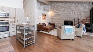 A spacious living area with a fireplace, a kitchen with modern appliances, and a loft space.