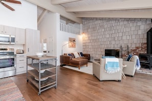 Uma sala de estar ampla com lareira, cozinha equipada com eletrodomésticos modernos e um espaço loft.