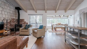 A spacious living area with a fireplace, a sofa, a dining table, and a kitchen area with a refrigerator.