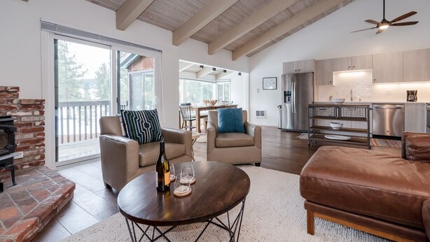 A spacious living area with a fireplace, leather sofas, a round coffee table, and a kitchen in the background.