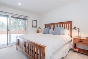 A bedroom with a wooden bed, a nightstand, a lamp, and a sliding glass door leading to a balcony.