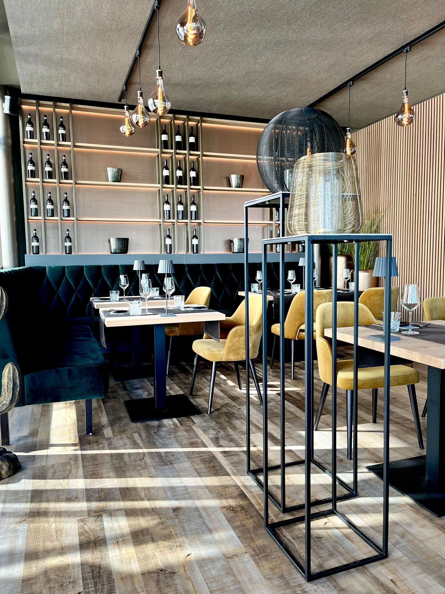 Un comedor moderno con piso de madera, una mesa central con sillas y una bodega en el fondo.