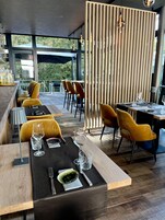A modern restaurant with wooden furniture, glassware, and a view of the outdoors.