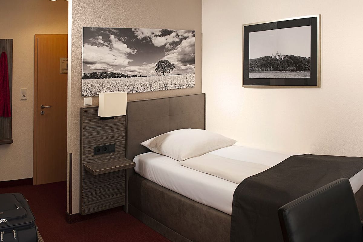 Ein Hotelzimmer mit Bett, Kopfteil, Wandbild und Tür.