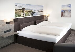 Un dormitorio moderno con una cama grande, dos mesitas de noche y dos lámparas de pared.