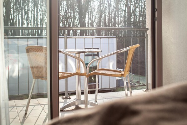 A balcony with two wicker chairs and a small table. - Parkhotel Ahrbergen (Giesen)