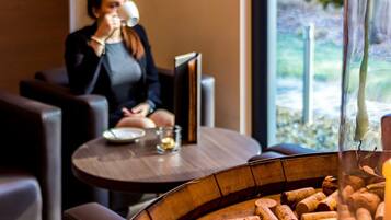 A cozy indoor setting with leather seating, a table with a candle and a glass, and a view of greenery outside.