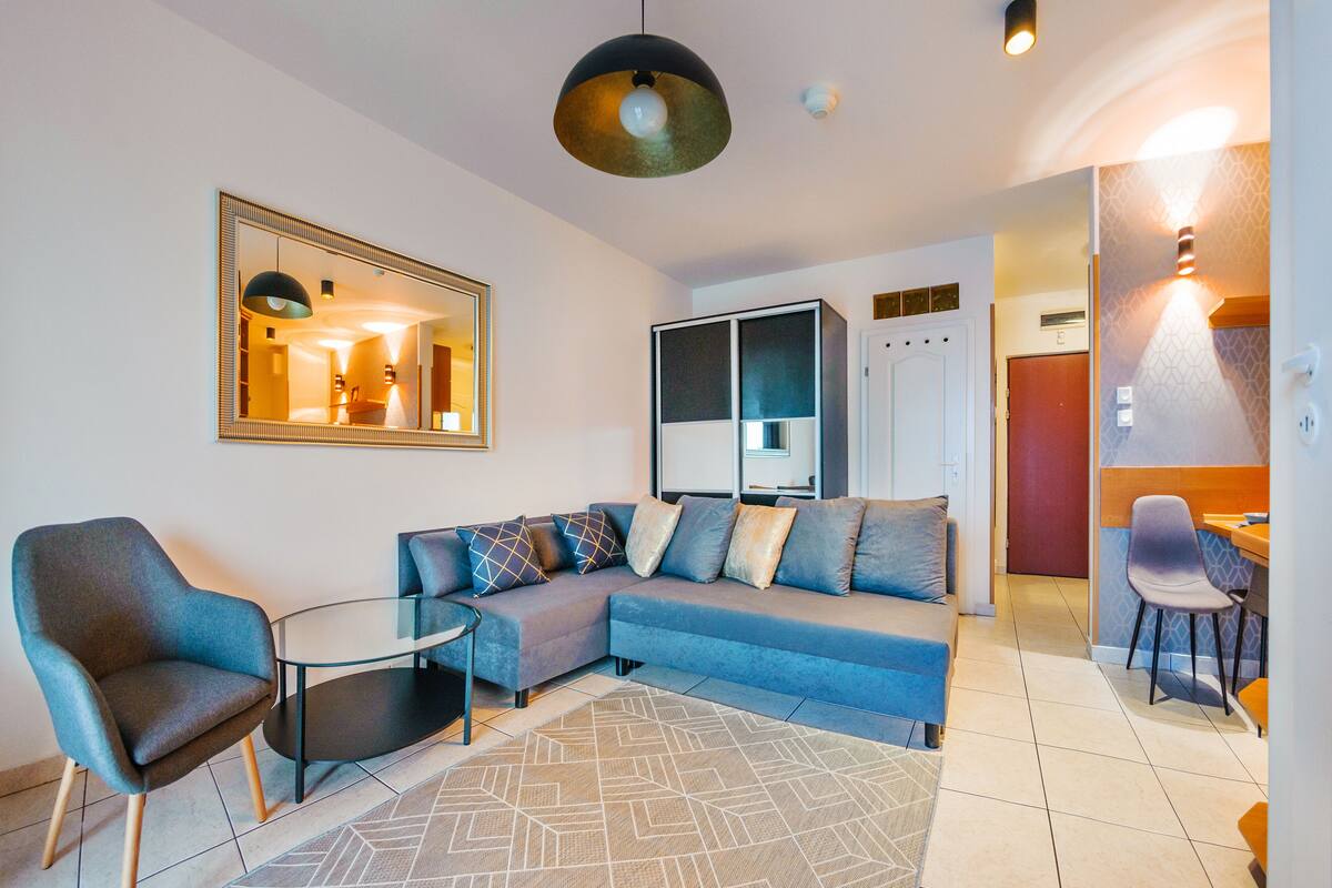 A modern living room with a sectional sofa, a glass coffee table, and a blue armchair.