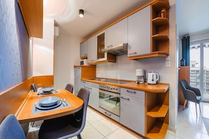 Une cuisine moderne avec des meubles gris, un plan de travail en bois et un coin repas avec une table mise pour deux personnes.