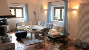 Ein gemütliches Wohnzimmer mit Sofa, Korbsessel, Couchtisch und Kamin.