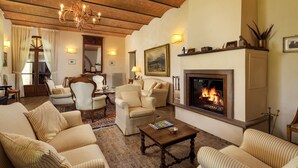 A cozy living room with striped sofas, a fireplace, and a chandelier. - Podere Maiano - Private Pool Villa with 9 Bdrs and Spa (Buonconvento, Siena)