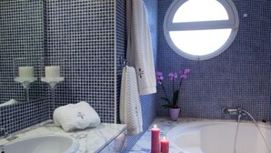 Une salle de bain avec un lavabo blanc, une baignoire et une fenêtre.
