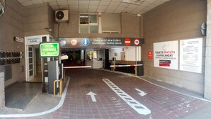L’entrée d’un hôtel, avec un distributeur de billets, des flèches indiquant la direction et un panneau indiquant que l’hôtel est ouvert de 7h00 à 23h00.