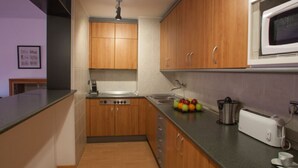 Une cuisine moderne avec des meubles en bois, un évier en acier inoxydable, un four à micro-ondes et un grille-pain.