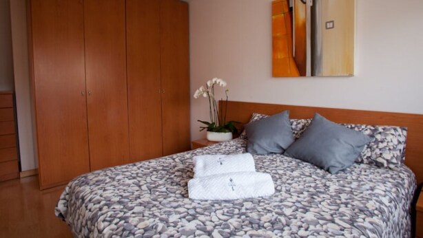 Une chambre à coucher avec un lit, une armoire, une plante en pot et un tableau accroché au mur.