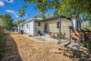 A single-story house with a covered patio area, a barbecue grill, and a fenced backyard.