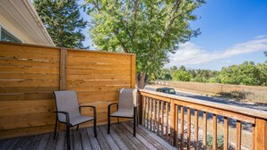 Une terrasse en bois avec deux chaises et une vue sur une route et des arbres.