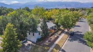 Un quartier résidentiel avec une maison entourée d’arbres et une route.