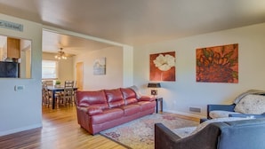 Un salon avec un canapé en cuir rouge, un canapé bleu et un coin repas doté de meubles en bois.