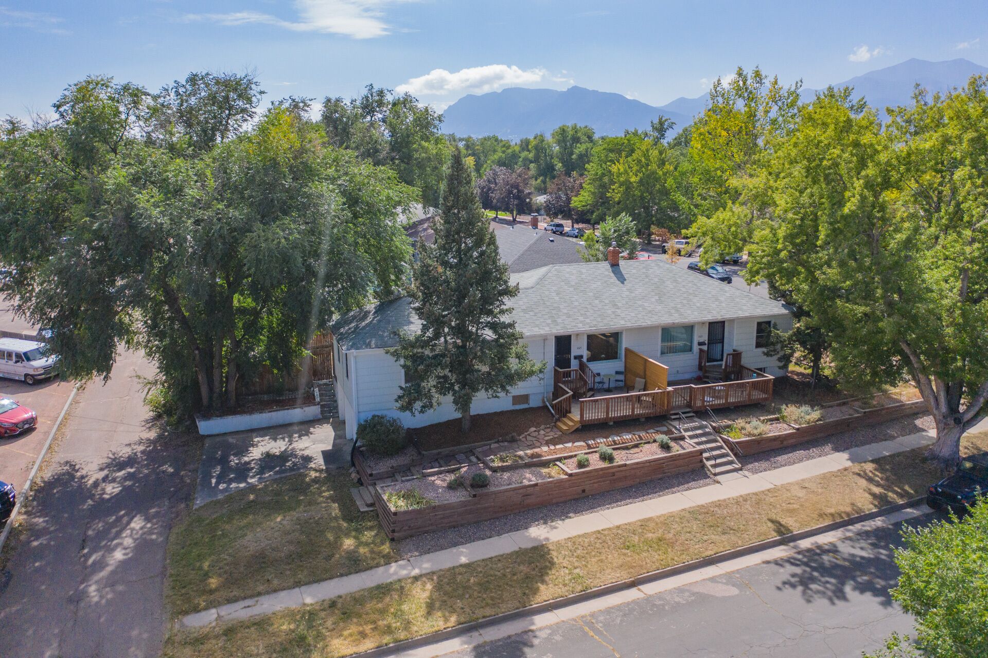 A single-story house with a porch, surrounded by trees and a mountain in the background.