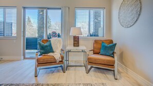A room with two leather armchairs, a small table with a lamp, and a large window with blinds. - 4BR Mnt Viewsmodern Urbanityrooftop Patio (Colorado Springs)