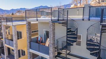 A multi-story residential building with a modern design, featuring balconies, a stone facade, and a spiral staircase.