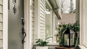 Eine überdachte Veranda mit einem Blumentopf, einer Laterne und einer Fußmatte.