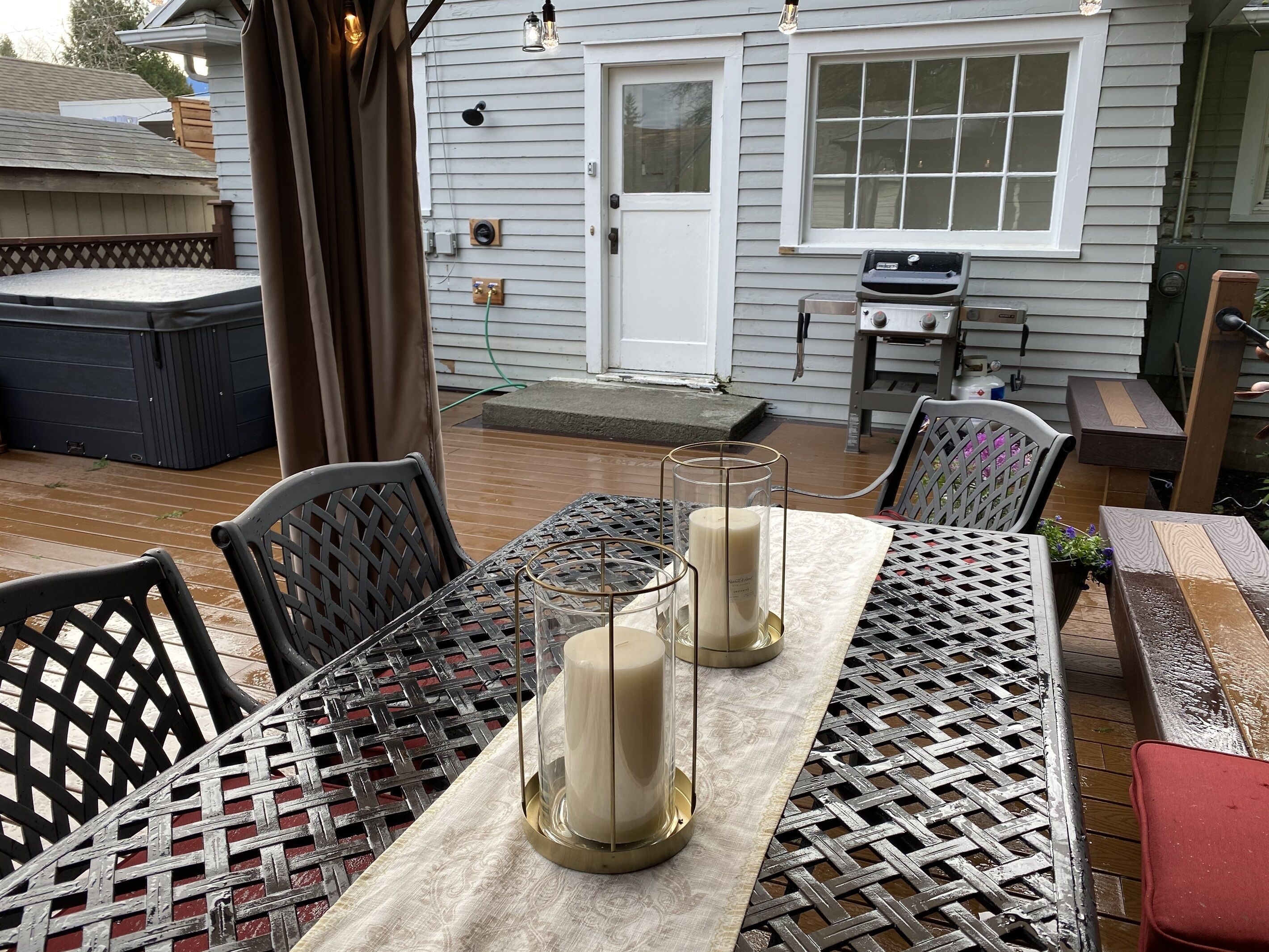 A patio with a table set for two, featuring a woven tablecloth and two candle holders.