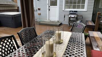 A patio with a table set for two, featuring a woven tablecloth and two candle holders.