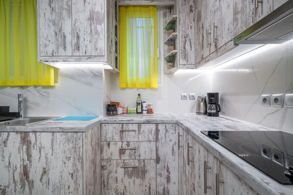 A kitchen with white cabinets, a yellow window shade, and a coffee maker.