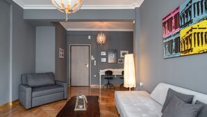 A modern living room with a grey sofa, a white sofa, a wooden coffee table, and a chandelier.