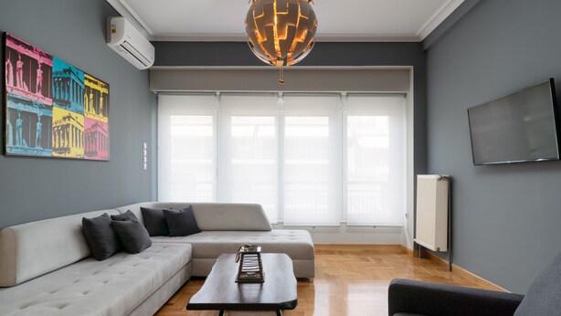 A modern living room with a sectional sofa, a coffee table, and a large window with blinds.