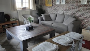 Un salón con un sofá gris, una mesa de centro de madera y un sillón blanco.
