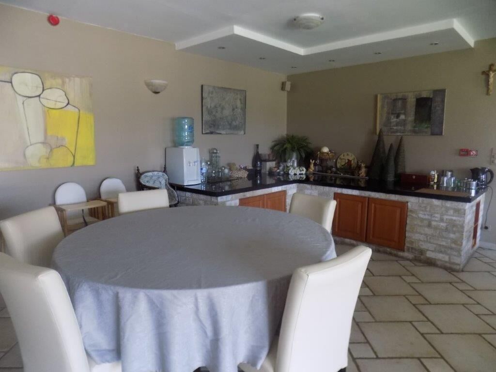 Un comedor con una mesa redonda y sillas, una cocina con encimera de piedra y obras de arte en las paredes.