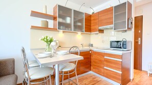 Una cocina moderna con armarios de madera, un microondas y un comedor con una mesa y sillas.