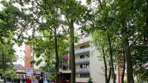 Calle bordeada de árboles y un edificio de varios pisos con balcones.