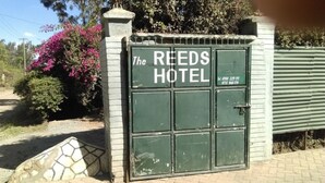 A green metal gate with "The REEDS HOTEL" written on it, along with a phone number. - The Reeds Hotel (Ongata Rongai)