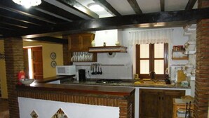 A kitchen with a wooden island, a microwave, and hanging utensils. - The rural house Tigre (Gaucín)