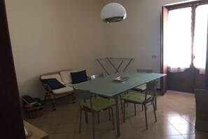 Un espace repas comprenant une table et des chaises, un canapé et un luminaire au plafond.
