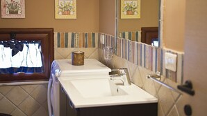 Ein Badezimmer mit einem weißen Waschbecken, einem Spiegel und einem Handtuchhalter. An der Wand hängen drei florale Bilder in Rahmen.