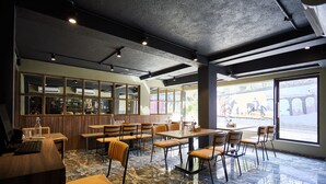 A restaurant with a stone floor, wooden furniture, and large windows offering a view of the street. - Aureole Mrida (Mawal)