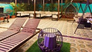 An outdoor patio with a swing, cushioned seating, and a decorative hanging sphere. - Aureole Mrida (Mawal)