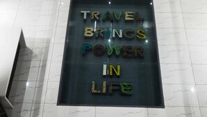 A sign with the text "TRAVEL BRINGS POWER IN LIFE" on a reflective floor. - Aureole Mrida (Mawal)